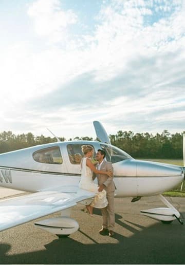 Couple celebrating a proposal beside an Ocean Isle Aviation airplane